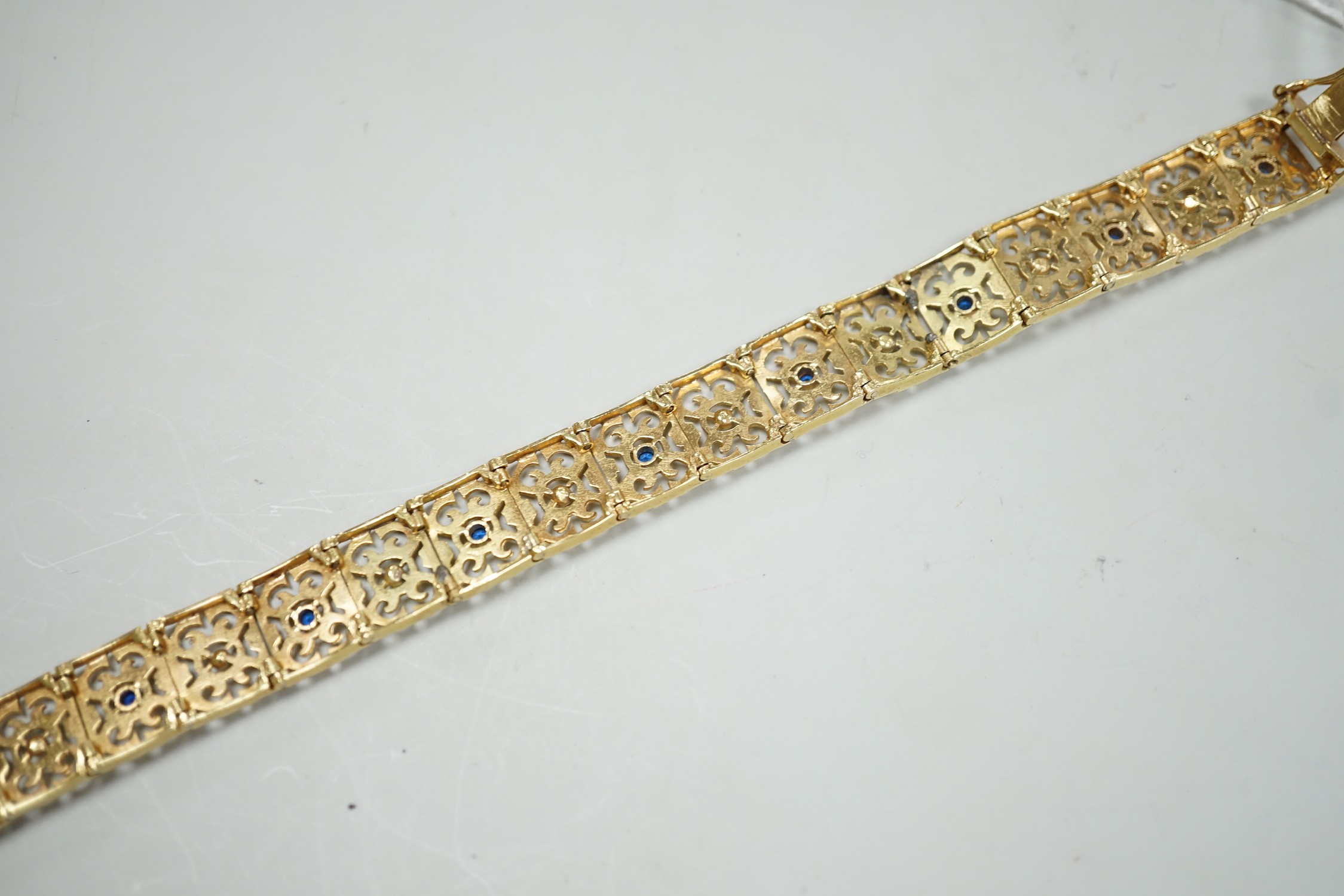 A modern pierced yellow metal and blue paste set bracelet, 19cm gross weight 28.2 grams.